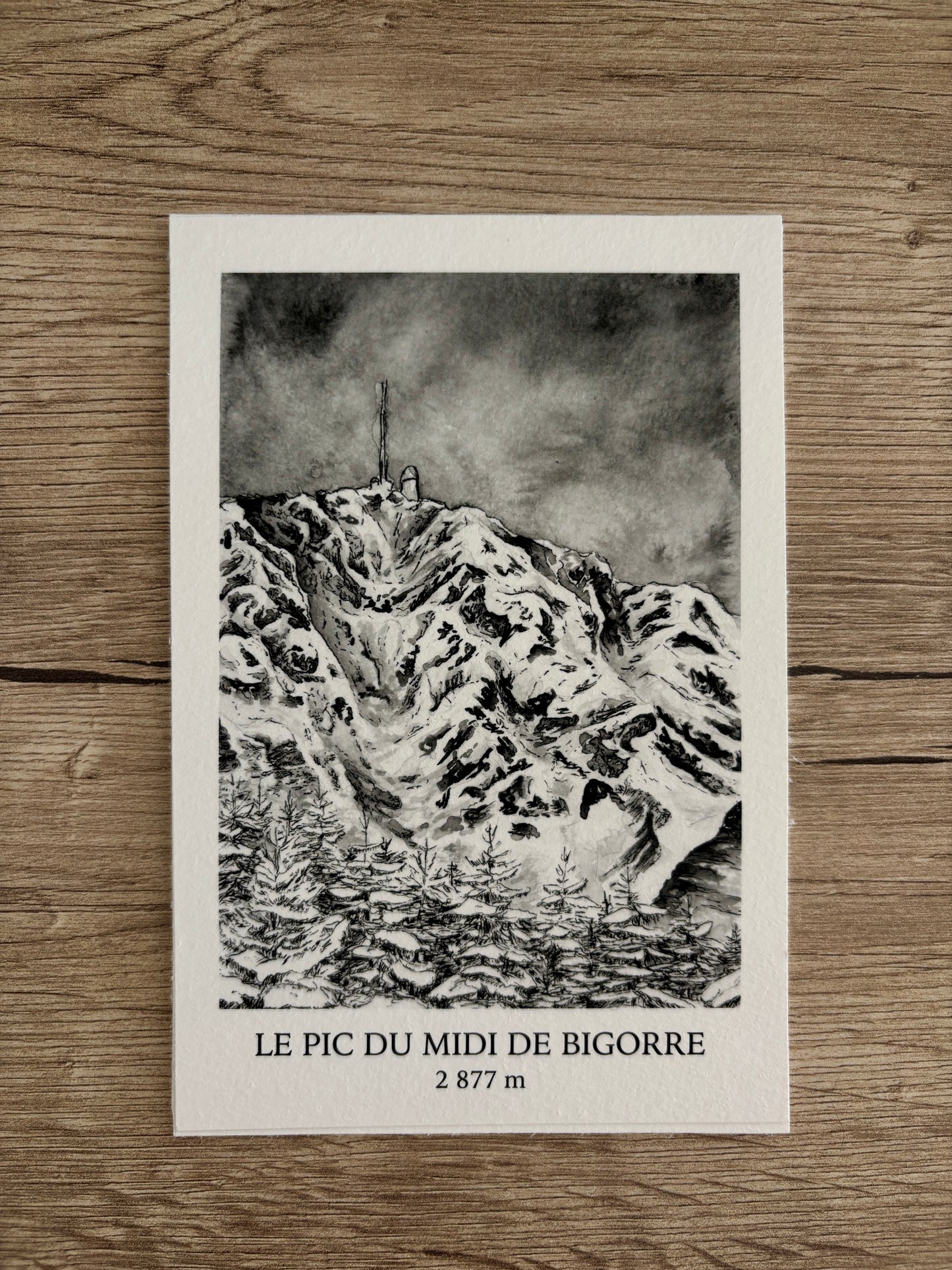 Ce troisième tirage fine art de cette série de tirages des Pyrénées représente le Pic du midi de Bigorre et sa forêt, on peut aussi apercevoir sur le haut de la montagne la bien connue antenne du Pic. Ce tirage en noir et blanc issu de la peinture originale du Pic du Midi de bigorre est encadré par des bordures blanches ajoutant un effet polaroid à la montagne. En dessous de la représentation de ce sommet se trouve le nom de la montagne ainsi que son altitude.