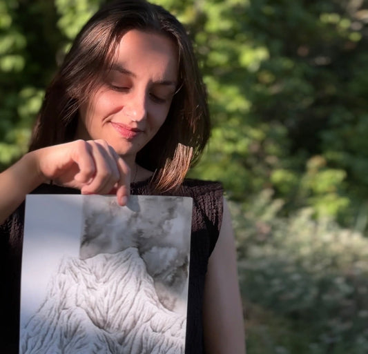 L'artiste Coline Pratviel avec le tableau intitulé "Puissance" une montagne en noir et blanc réalisée à l'encre de chine sur le thème de la puissance intrinsèque
