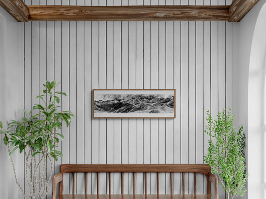 Peinture du panorama depuis le Pic de Bacanère en monochrome, peinte à l'encre de chine. Le tableau est affiché au dessus d'un banc en bois et est entouré d'arbres contribuant à une décoration murale calme, naturelle et sophistiquée