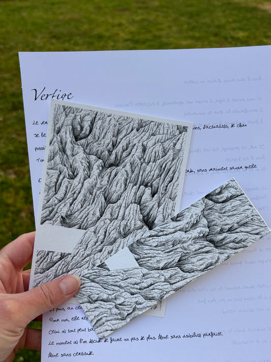 Apercu de la correspondance à l'encre des cimes du mois d'avril nommée vertige , ont peut voir sur cette image la lettre manuscrite du mois, l'impression fine art au format 10 x 15 cm ainsi que le marque page tiré de la peinture originale. Les 3 sont tenus par une main au-dessus d'herbe. idée cadeau montagne, zen, cadeau peinture noir et blanc, correspondance mensuelle physique 