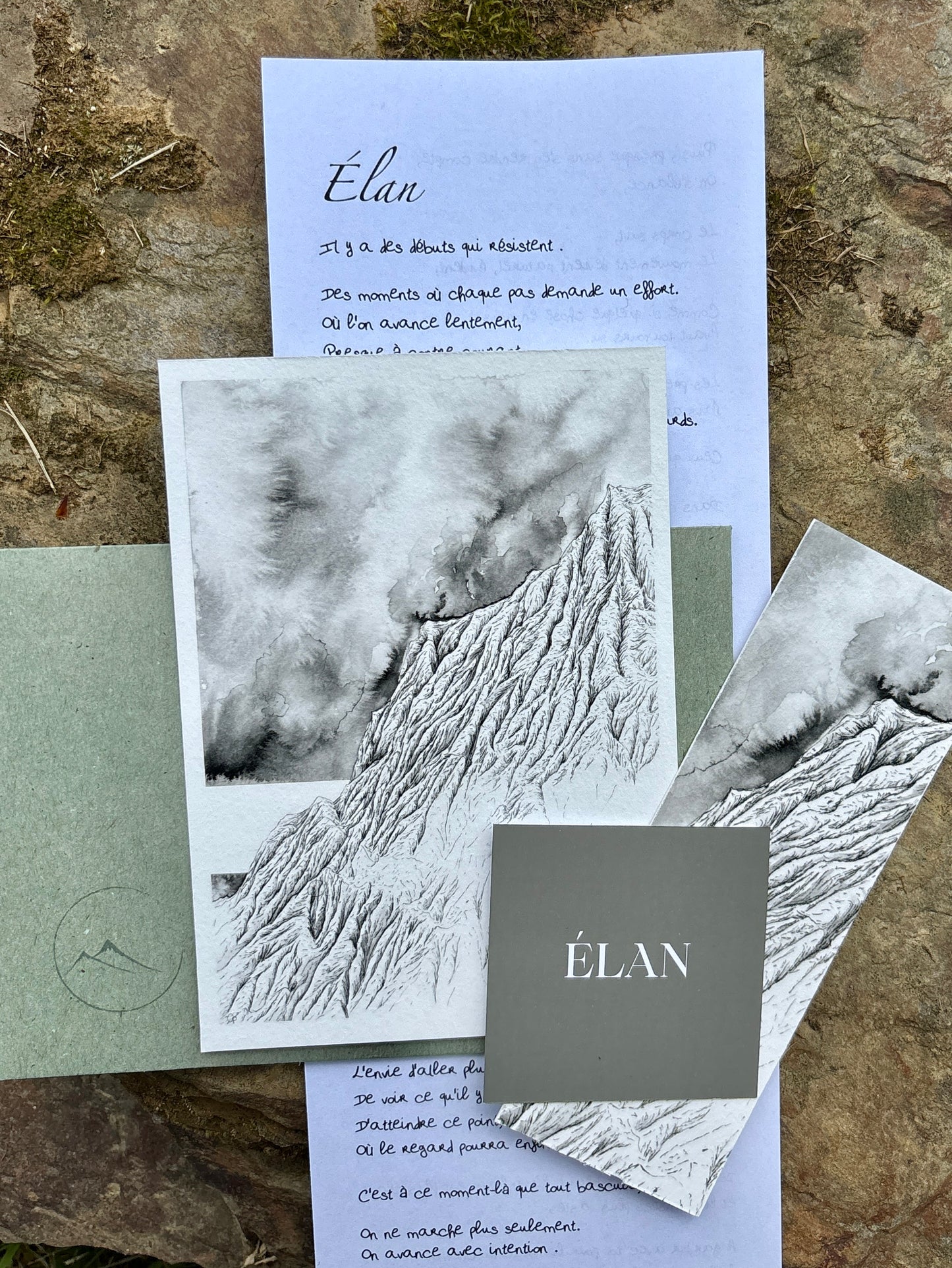 Edition "Elan" de la correspondance à l'encre des cimes réalisée par Coline Pratviel. On peut voir sur cette image le tirage d'art au format 10 x 15 cm du mois, la carte d'intention nommée "élan", le marque-page tiré de l'oeuvre mensuelle ainsi que la lettre manuscrite présentant le tableau, et l'émotion à sa base. L'enveloppe verte avec le logo de la correspondance est posée avec ces différents éléments artistiques sur une pierre naturelle faisant ressentir l'aspect proche de la nature 